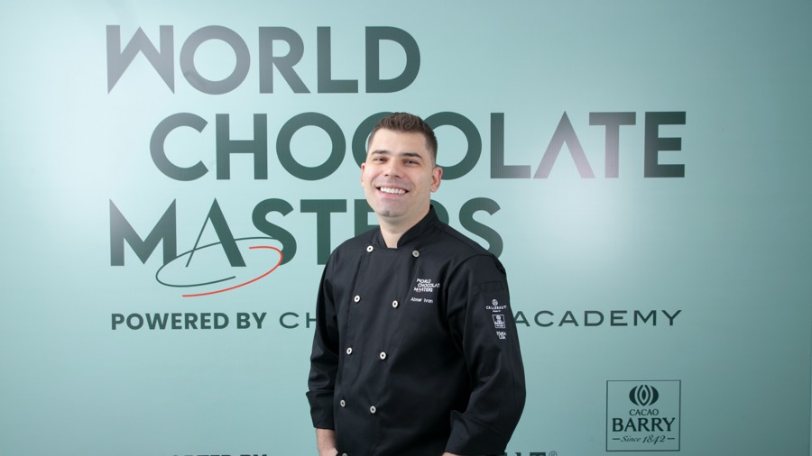 Chef Abner Ivan de dólmã preta, sorrindo diante do painel do World Chocolate Masters.